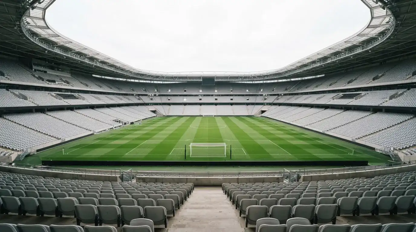Ein leeres Fußballstadion bei Tageslicht von der Tribüne aus gesehen, der Rasen zeigt gleichmäßige Mähstreifen.