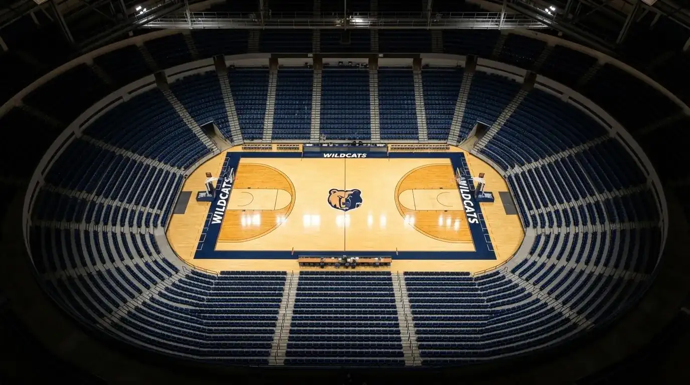 Eine Basketballhalle aus der Vogelperspektive mit leeren Sitzreihen und hell erleuchtetem Parkett.